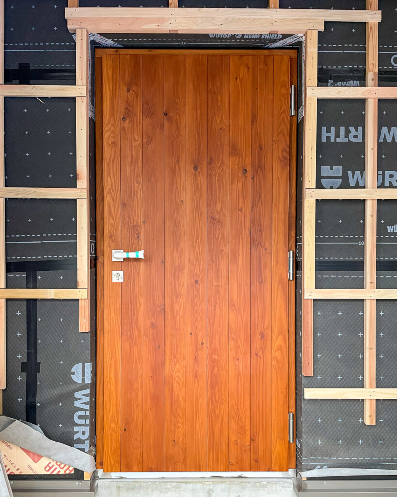 取手市の現場で木製玄関ドアを施工する写真